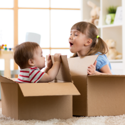 two kids playing in cardboard boxes