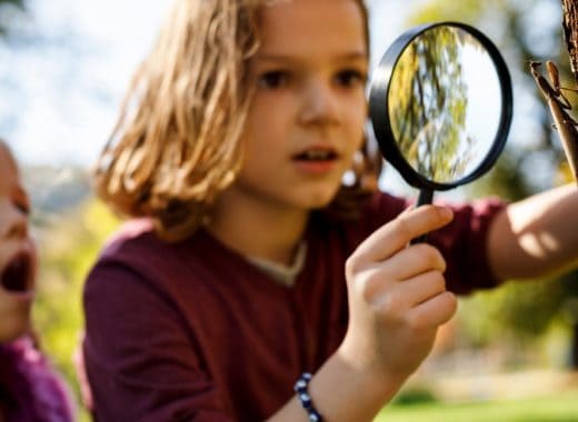 Two girls look through a magnifying glass for kids.