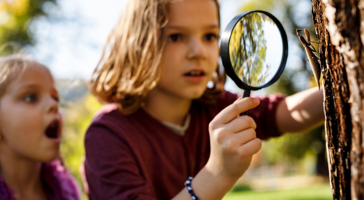 Two girls look through a magnifying glass for kids.