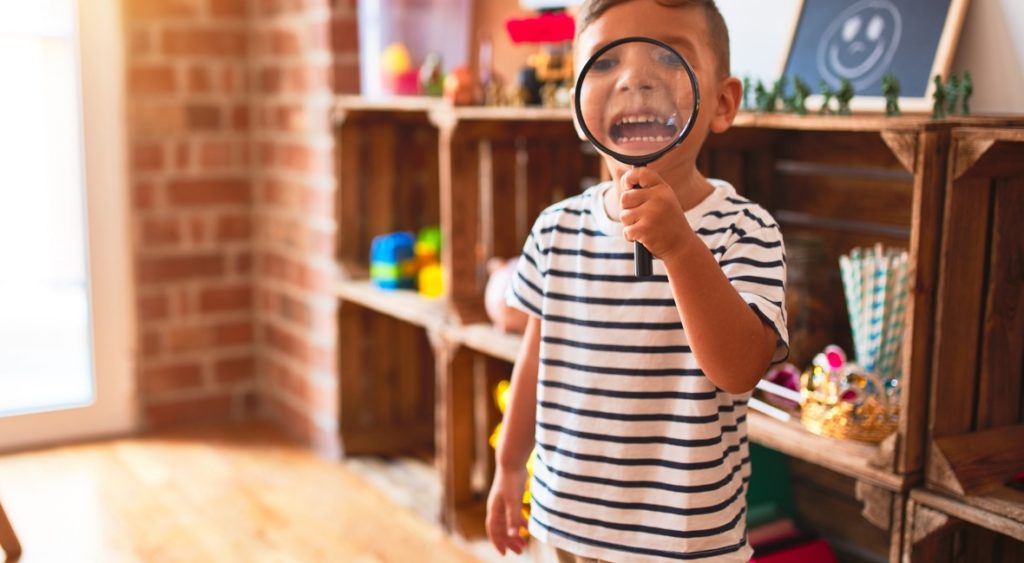 A boy looks through a magnifying glass for kids.