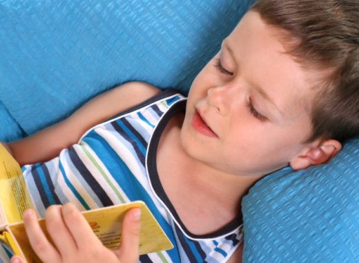 A boy is reading with a kids reading pillow.