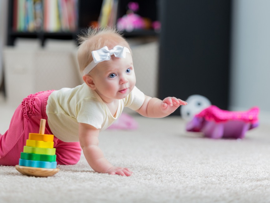 A baby crawls after a crawling baby toy.