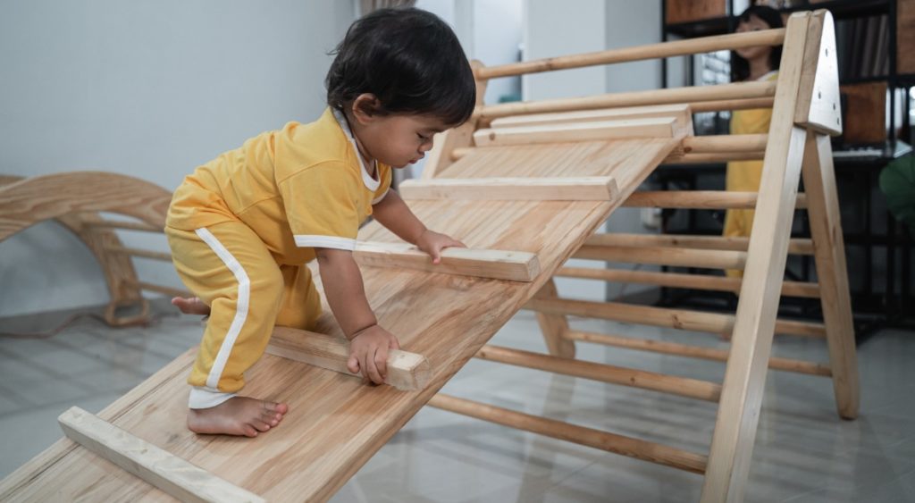 baby climbing on wooden climber