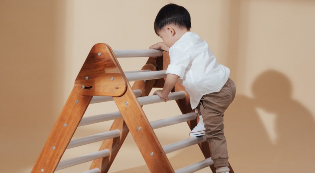 kid climbing on an indoor wooden climber