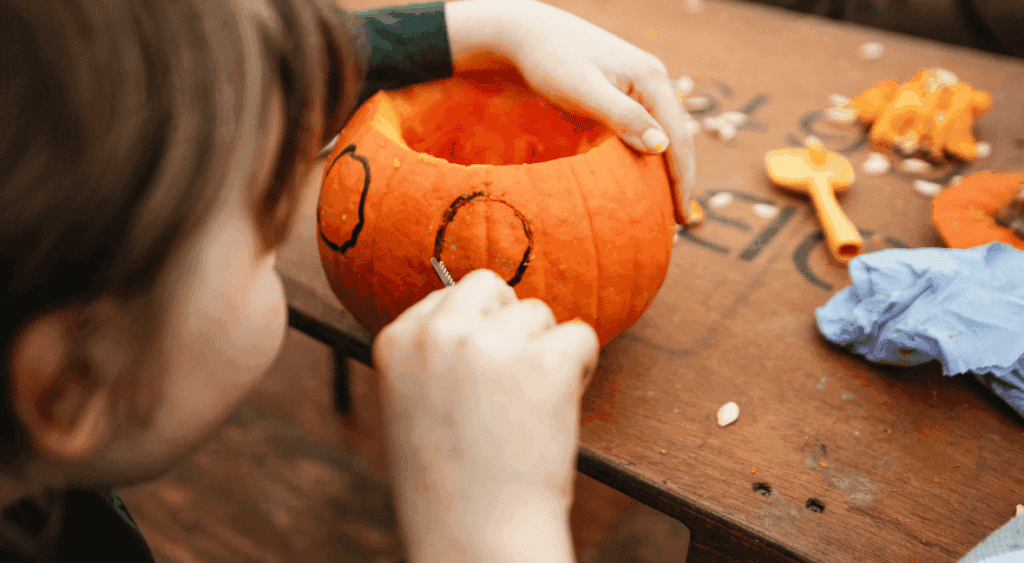 kid carving a pumpkin for a Halloween activity